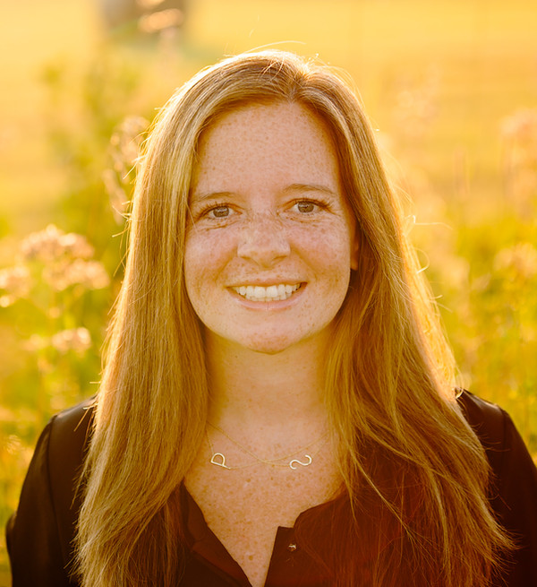 Anna Haskins outdoors in warm evening light, wearing a black top.