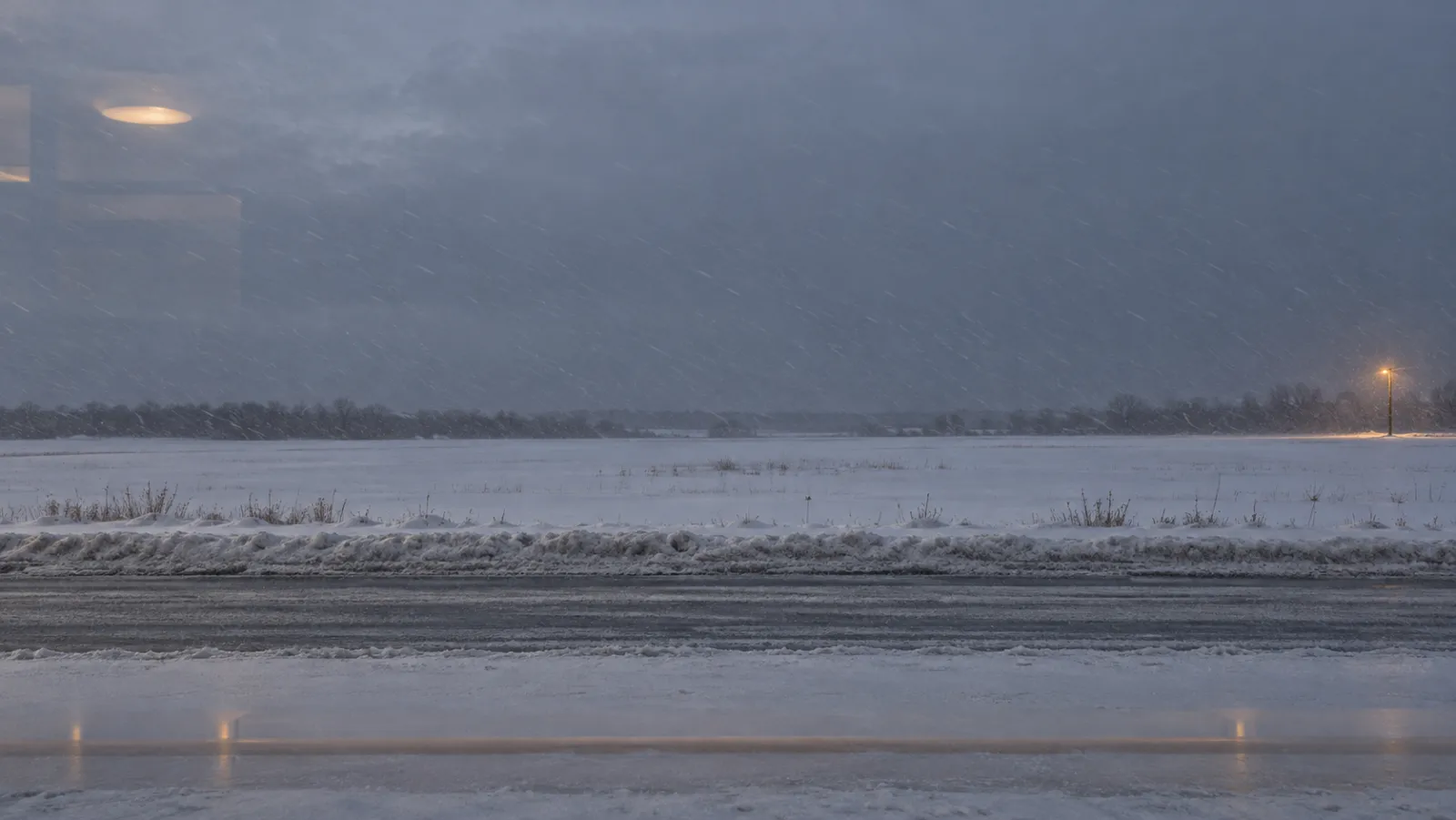 Illustrative snowy field and roadside through glass, with faint studio light reflections.